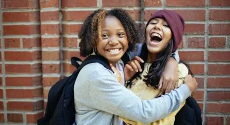 Two young people hugging in front of a brick wall