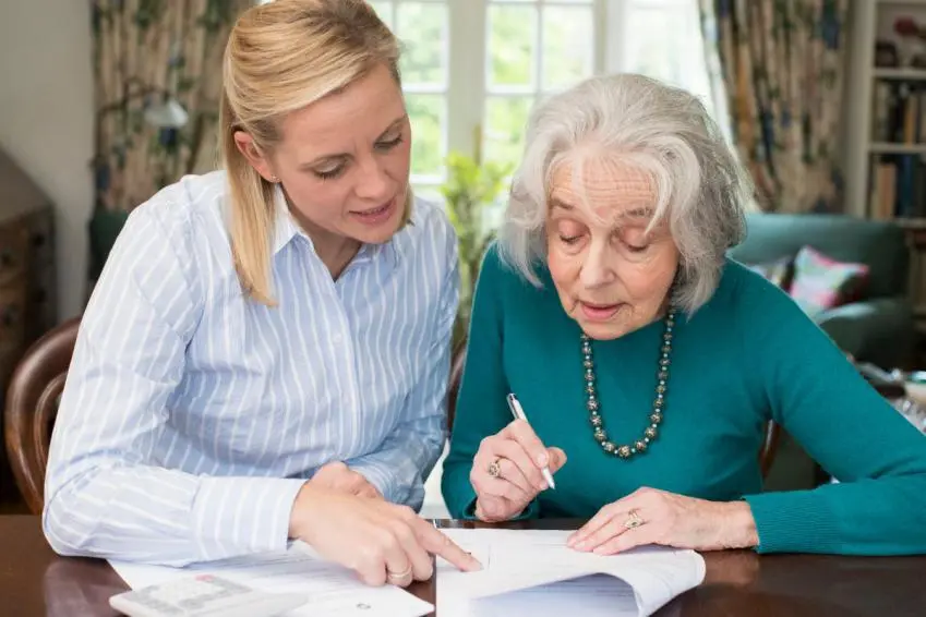 Woman helping an older woman with paperwork