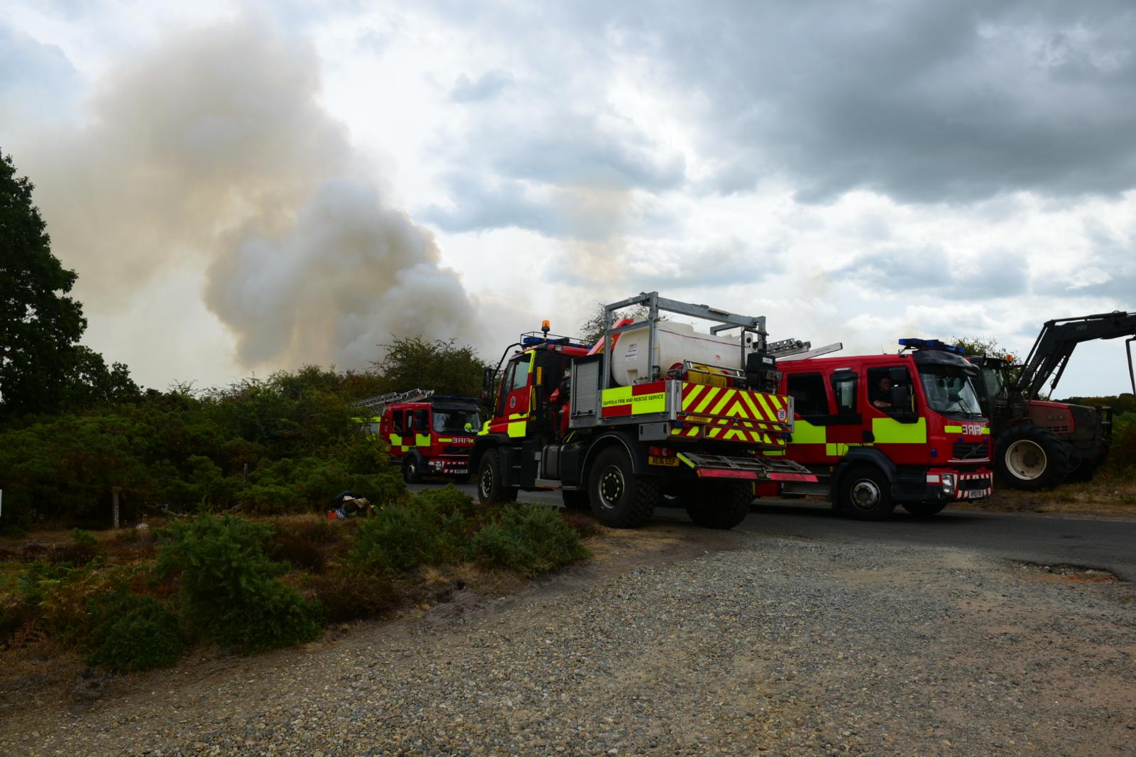 three fire appliances in heathland with smoke in the background