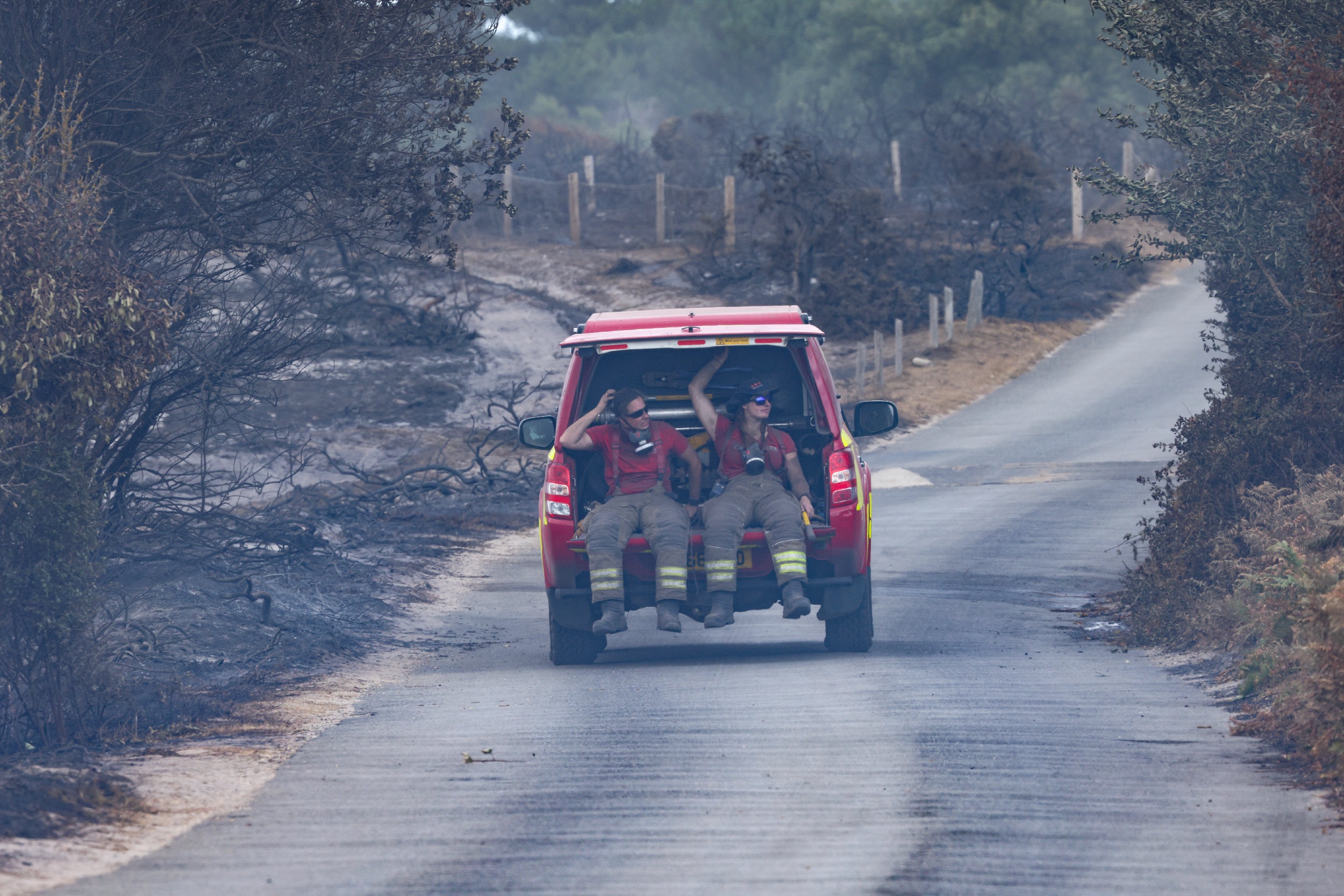 two firefighters sit in the back of a support vehicle
