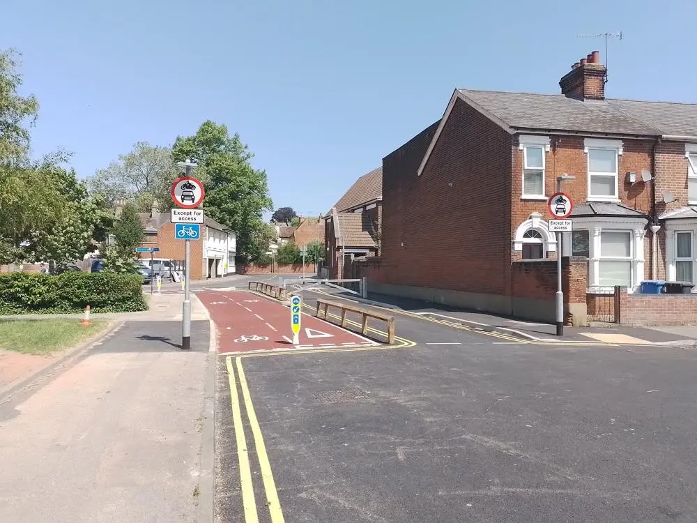 Two cycle lanes heading away from the camera with terraced housing on the right.