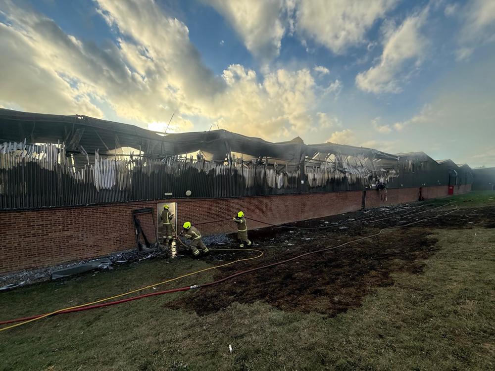 Three firefighters using hoses on a fire-damaged building