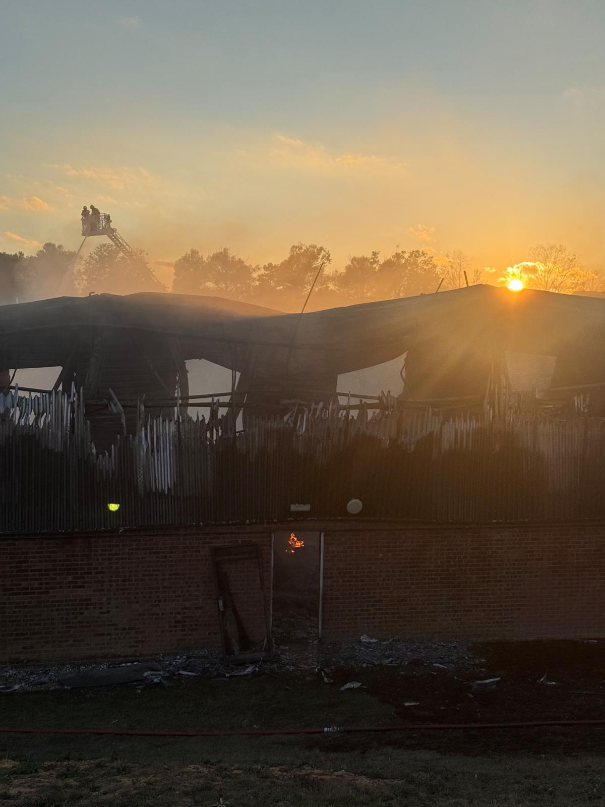 A fire-damaged building with flames visible through a doorway.