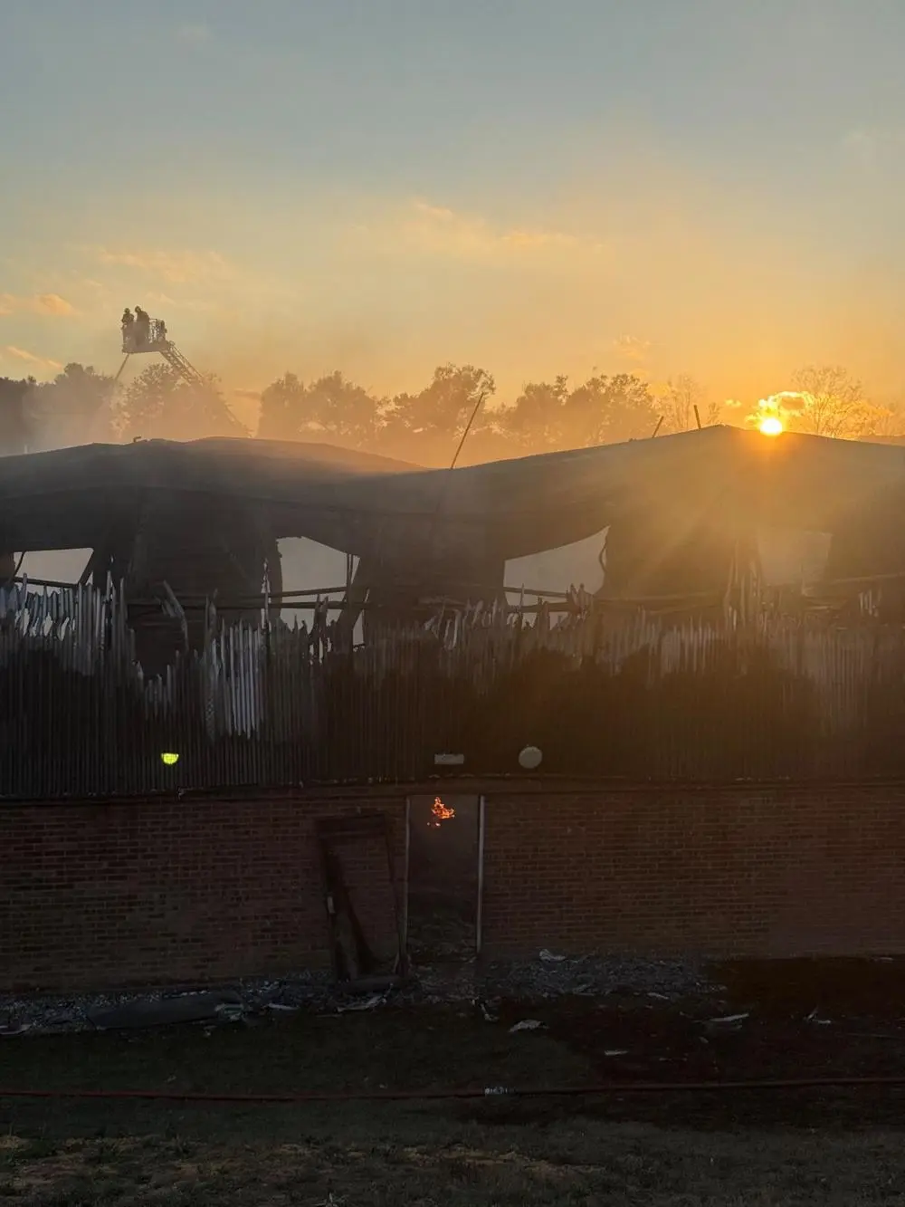 A fire-damaged building with flames visible through a doorway.