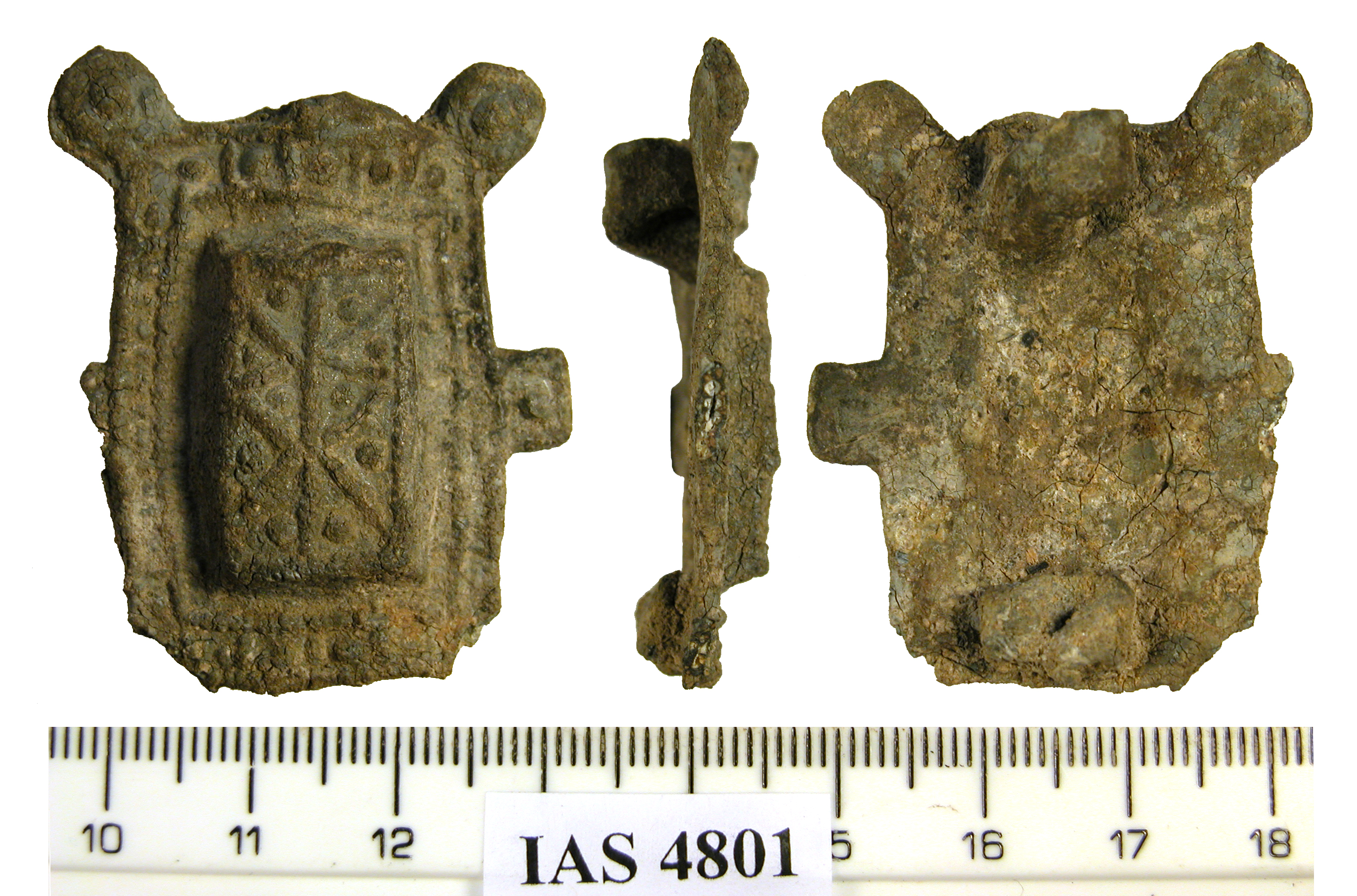 An early medieval lead brooch shown from three angles with a ruler for scale