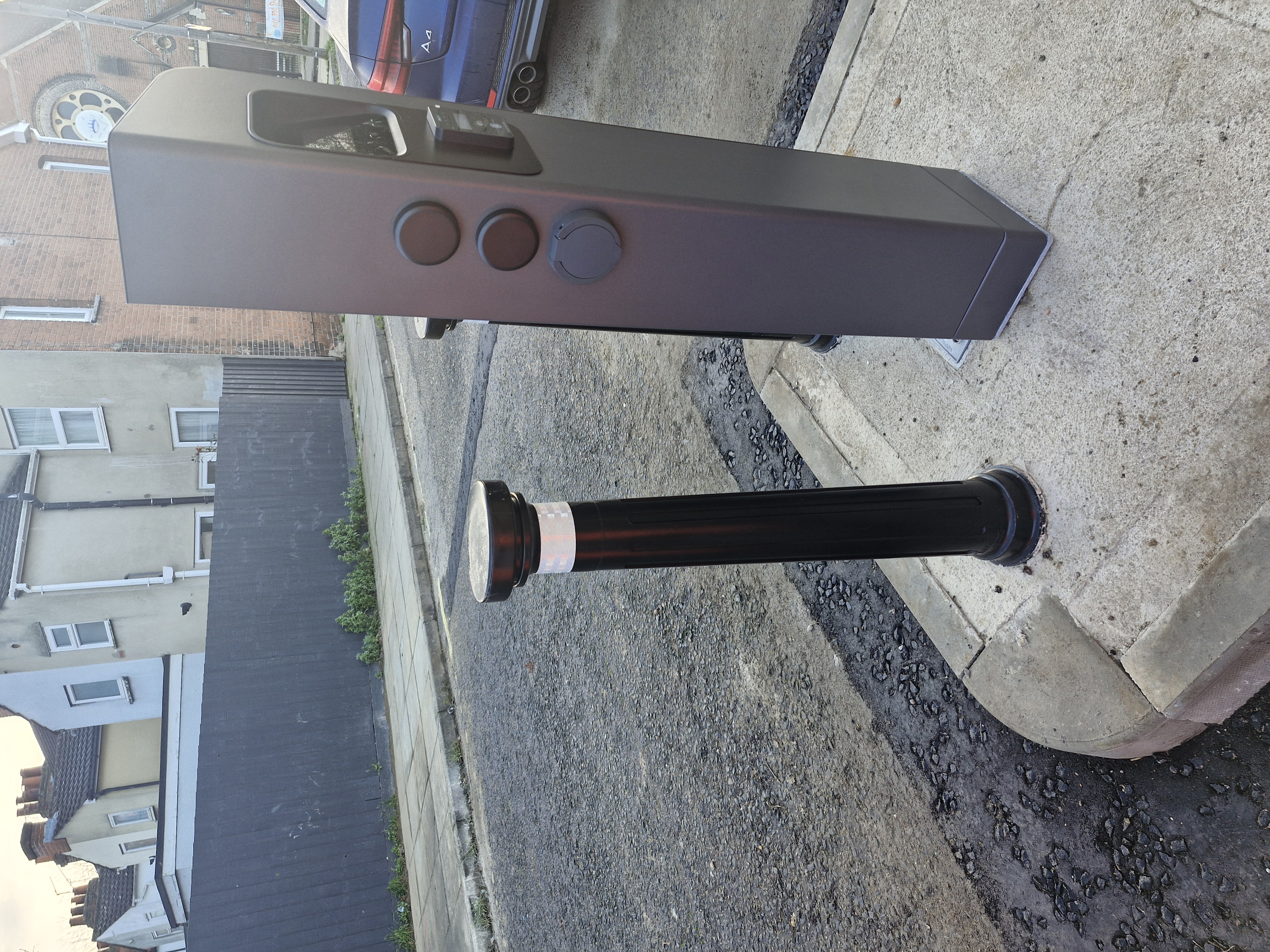 A charegepoint side on, with a picture of a socket to plug in a car. There is a bollard adjacent to the chargepoint.