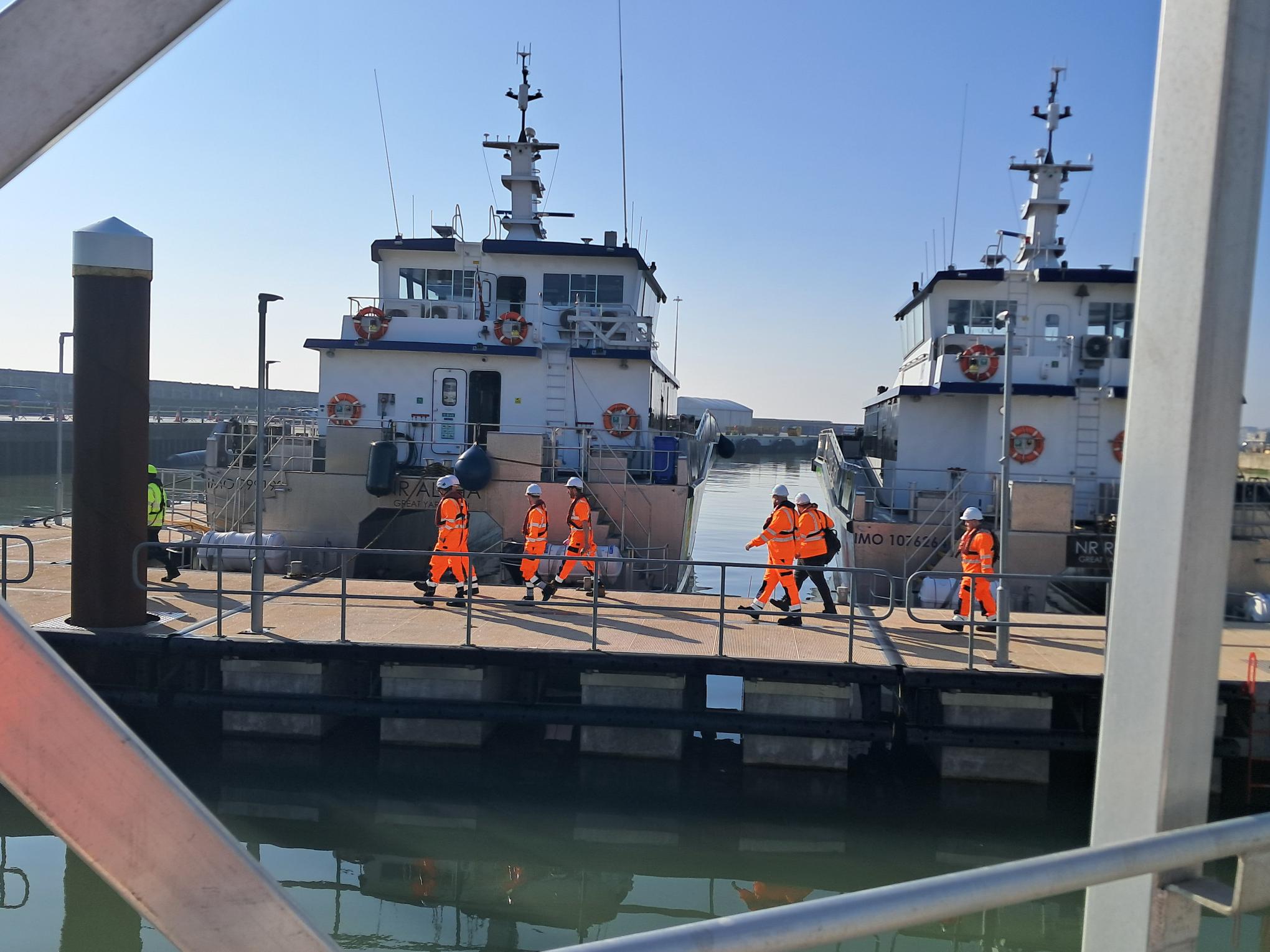 The cohort walking along the port in safety uniform