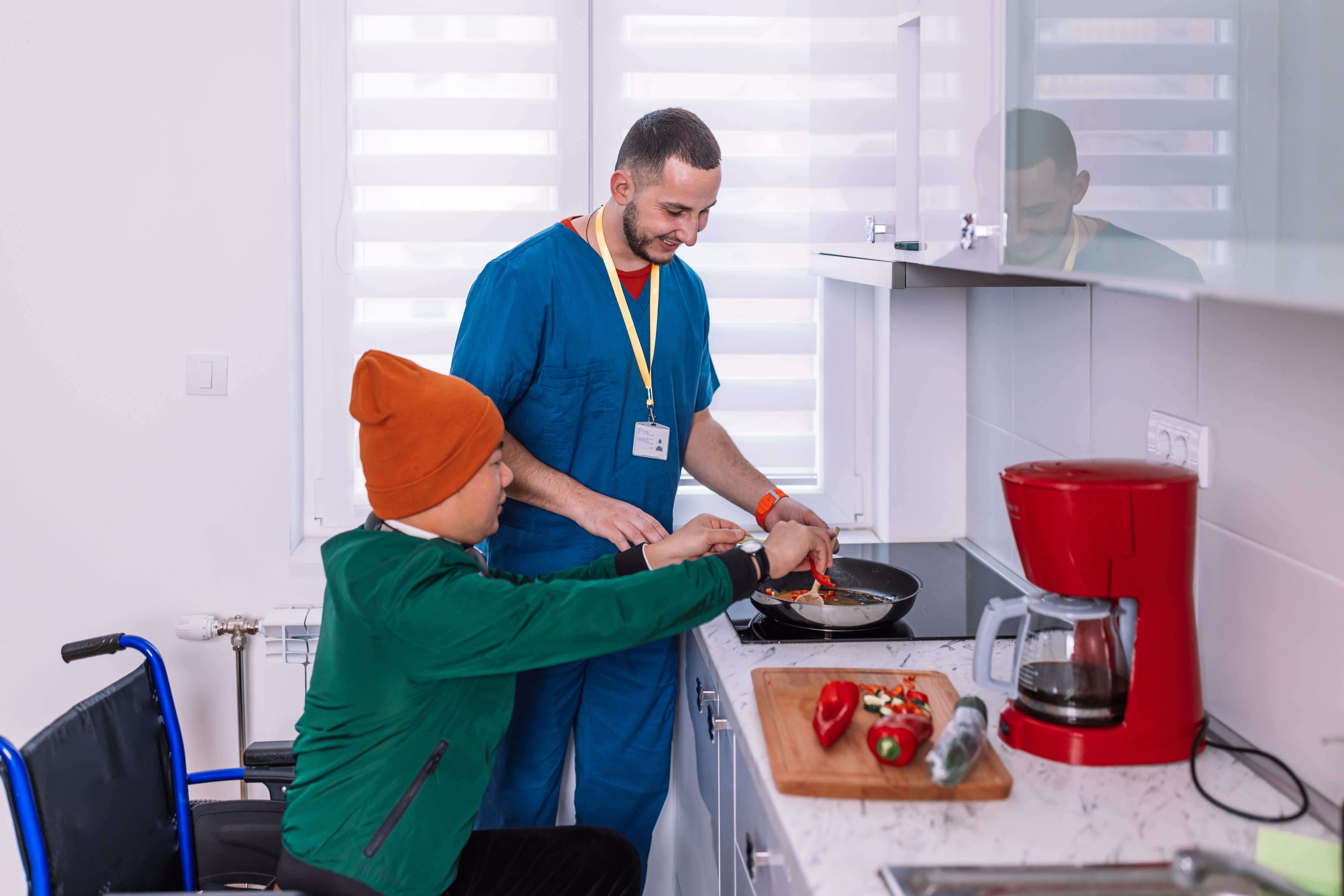 A man with learning disabilitiles cooking with a care worker. 