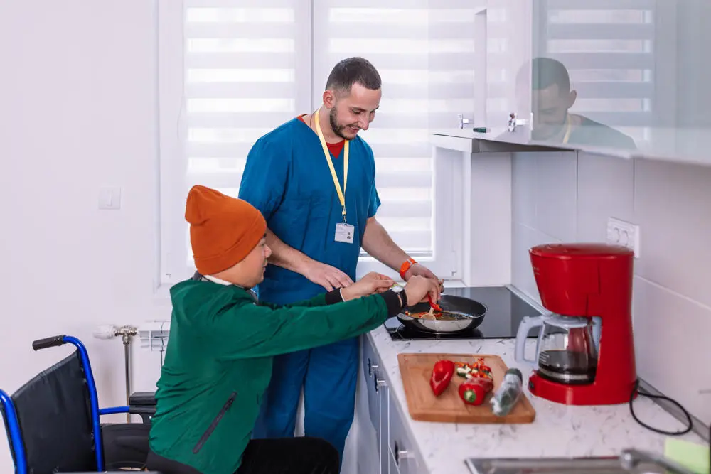 A man with learning disabilitiles cooking with a care worker.