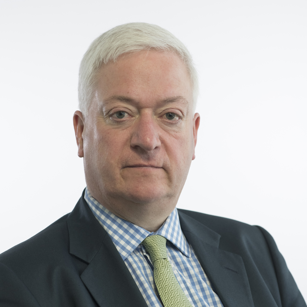 Alexander Nicoll, Councillor, wearing dark suit jacket and check shirt with a patterned tie. 