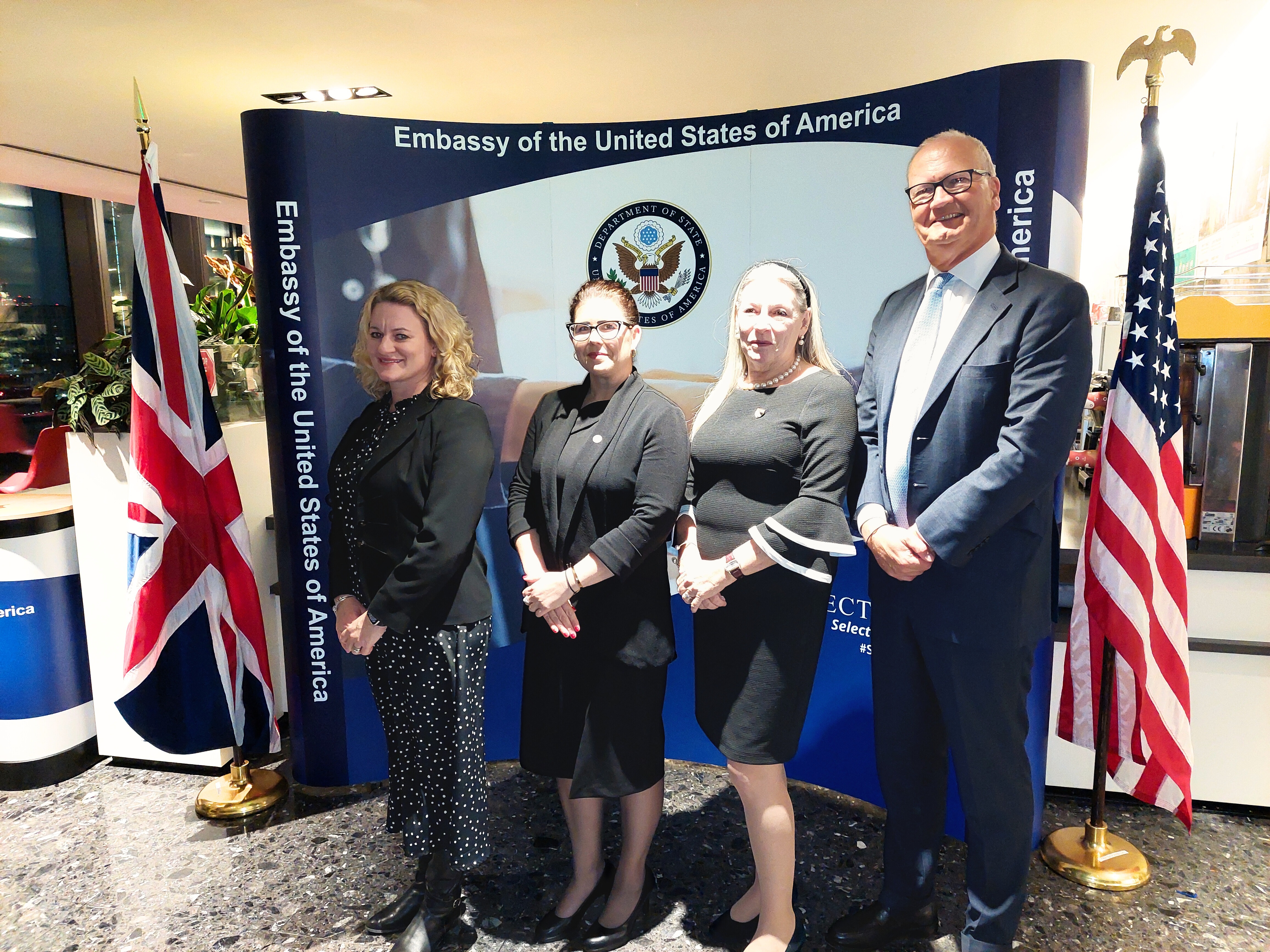 The signatories stand in front of a display at the US Embassy