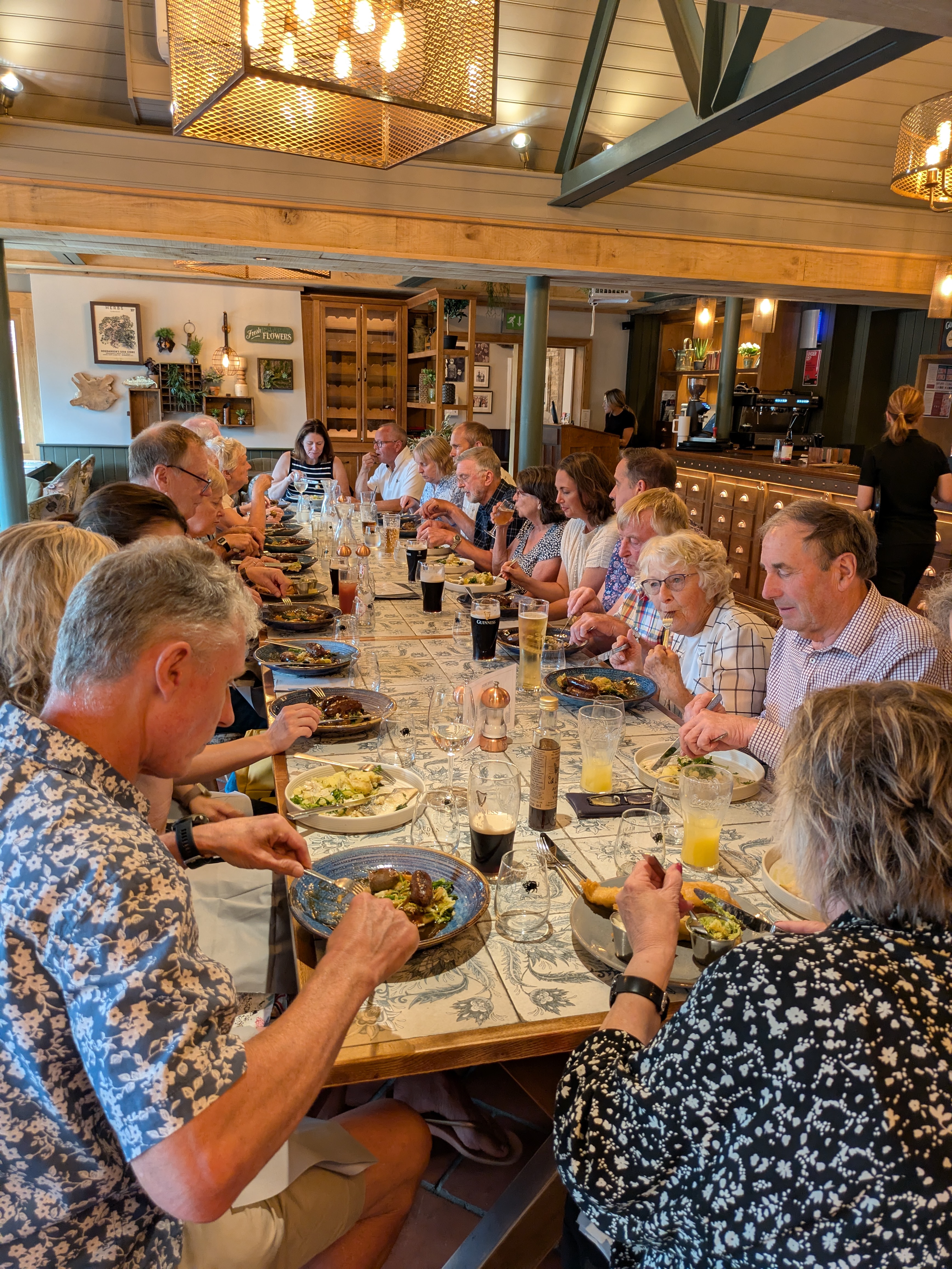 a group of twenty people enjoy a meal around a large table