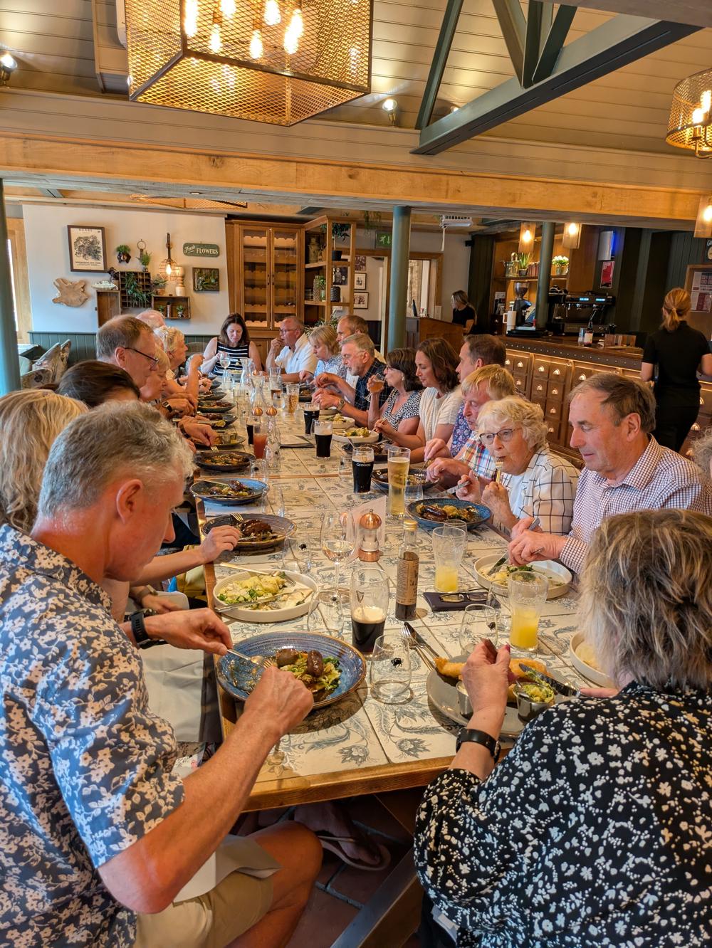 a group of twenty people enjoy a meal around a large table