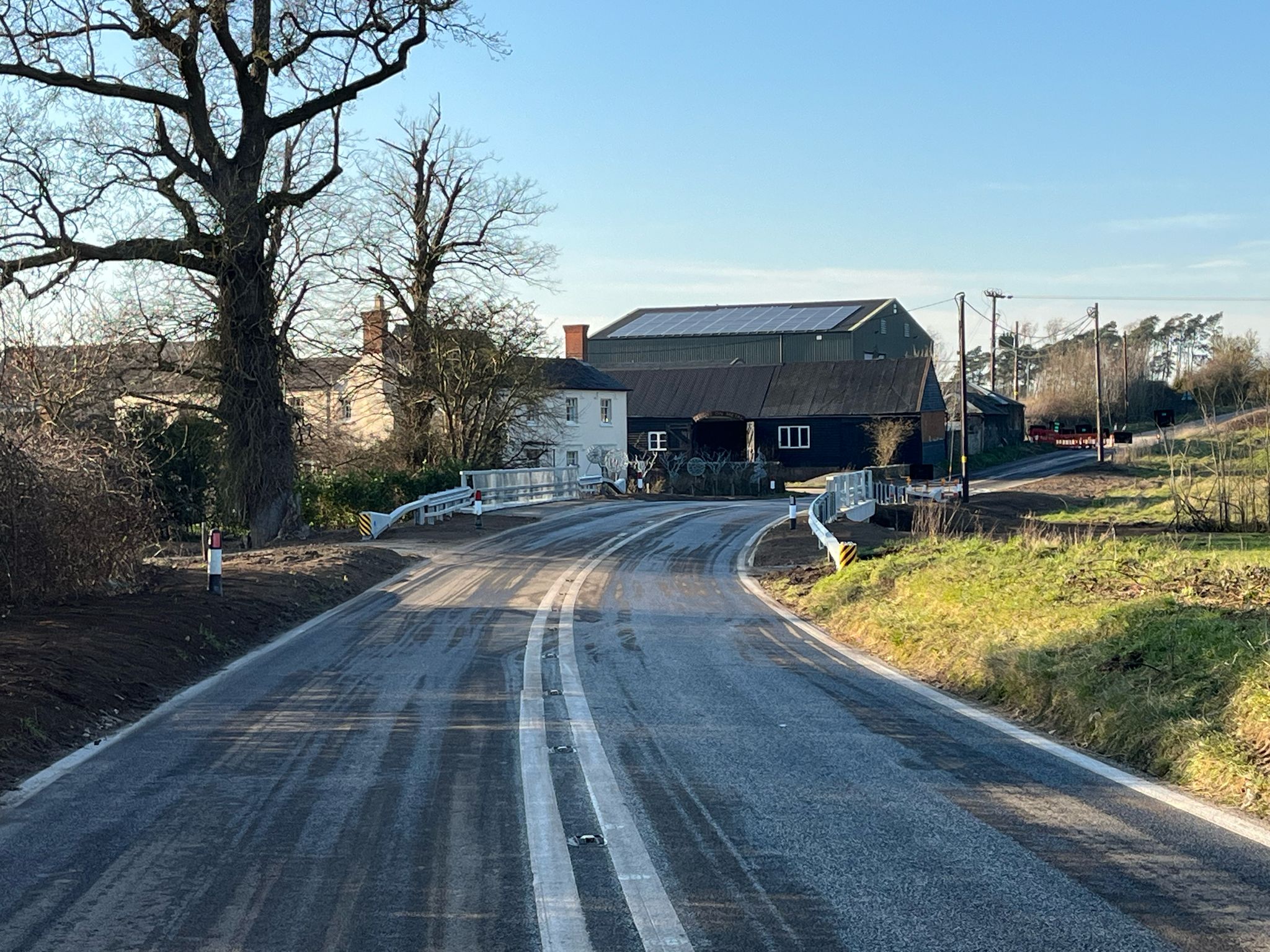 A new road bridge with a house and farm buildings in the background
