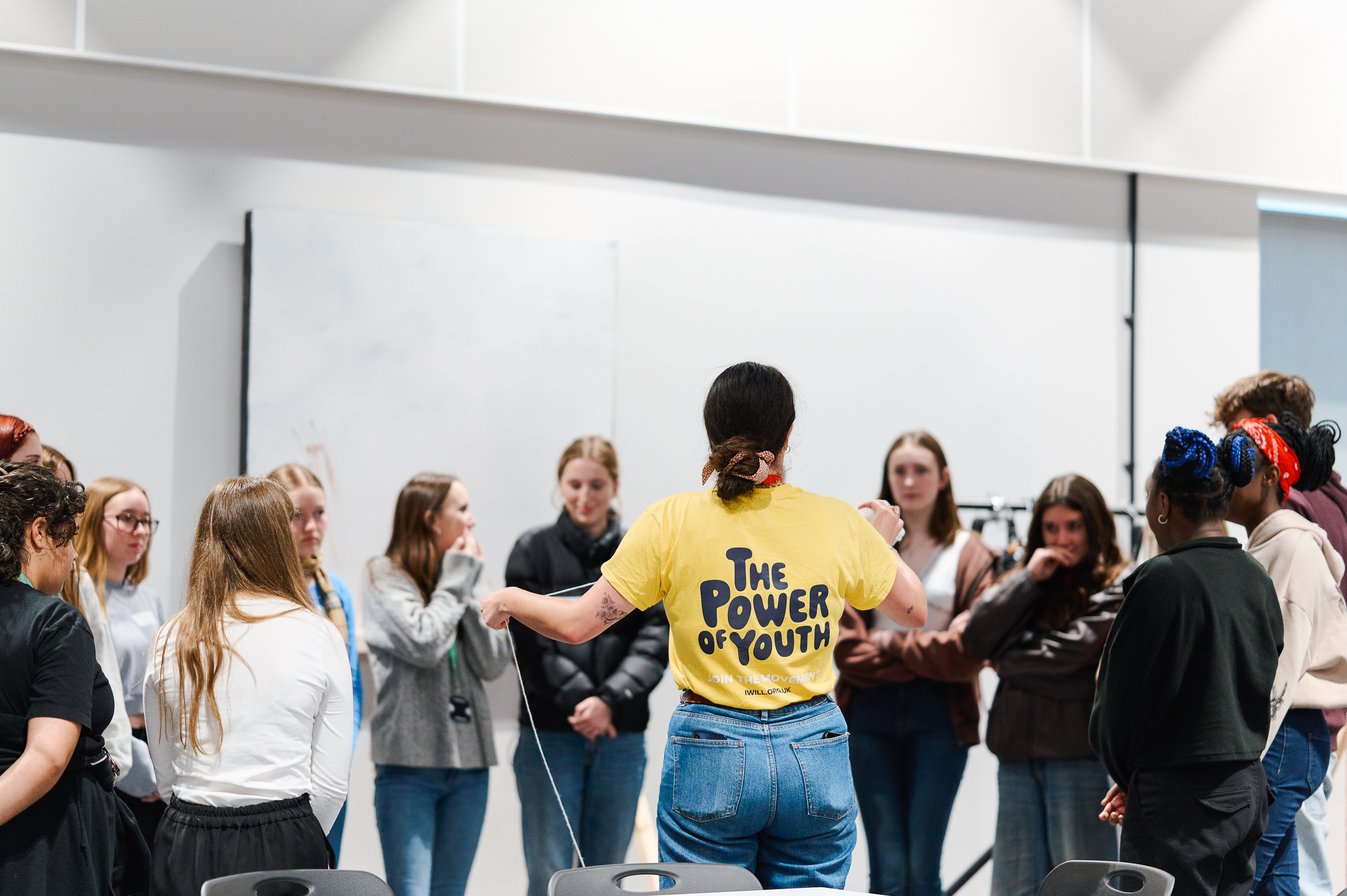 Woman with a yellow tshirt saying 'The Power of Youth' surrounded by young people
