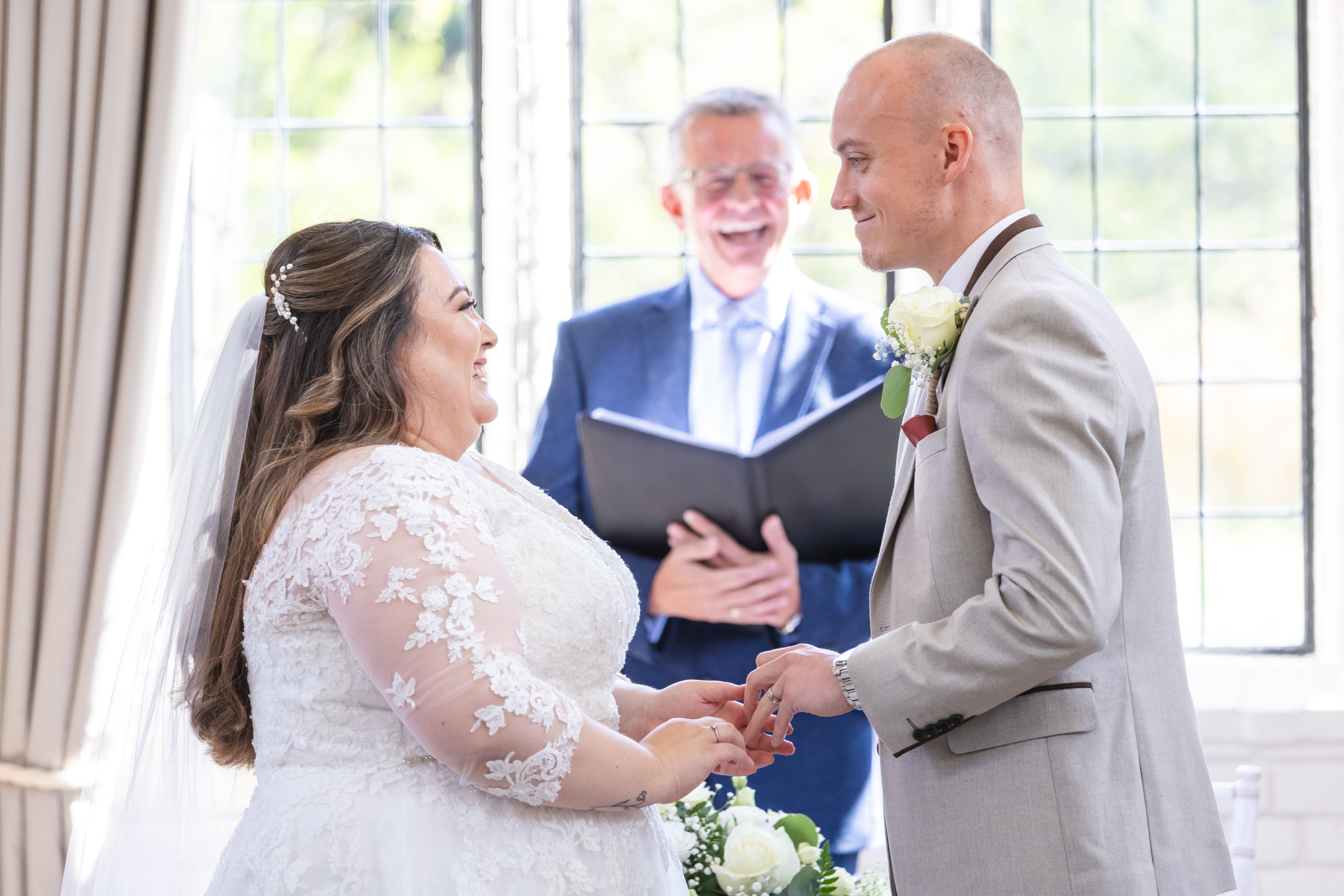 Celebrant laughing with bride and groom during wedding ceremony