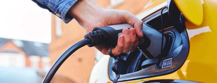 A yellow car charging at an EV chargepoint. 