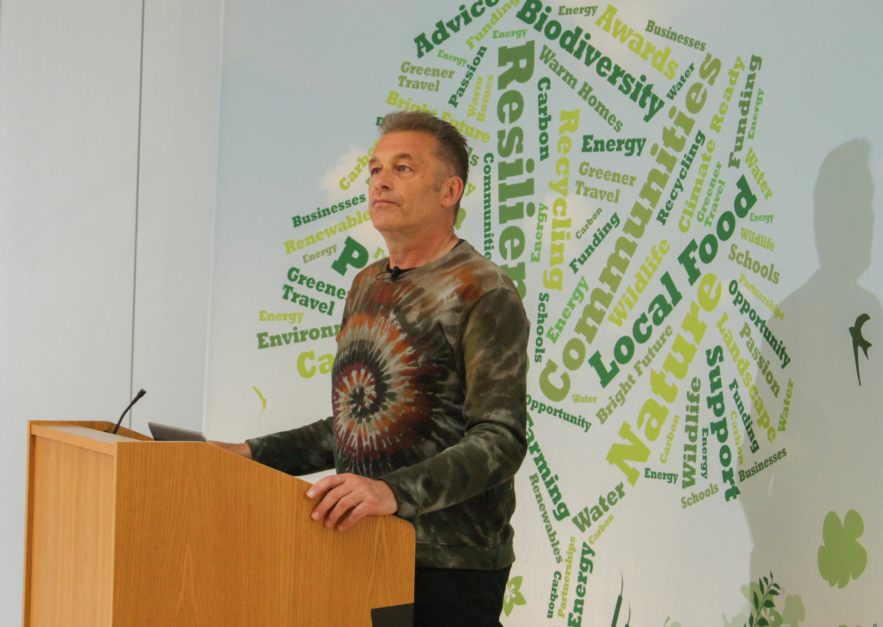 Chris Packham stands at a podium and delivers his speech