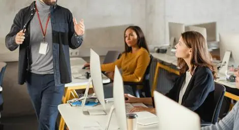 A teacher is working with two students who are using computers