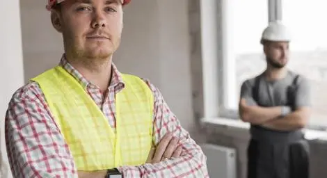 A construction worker is looking at us with his arms crossed