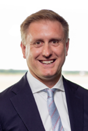 Dr Ed Garrett wearing dark jacket, light shirt and silver tie