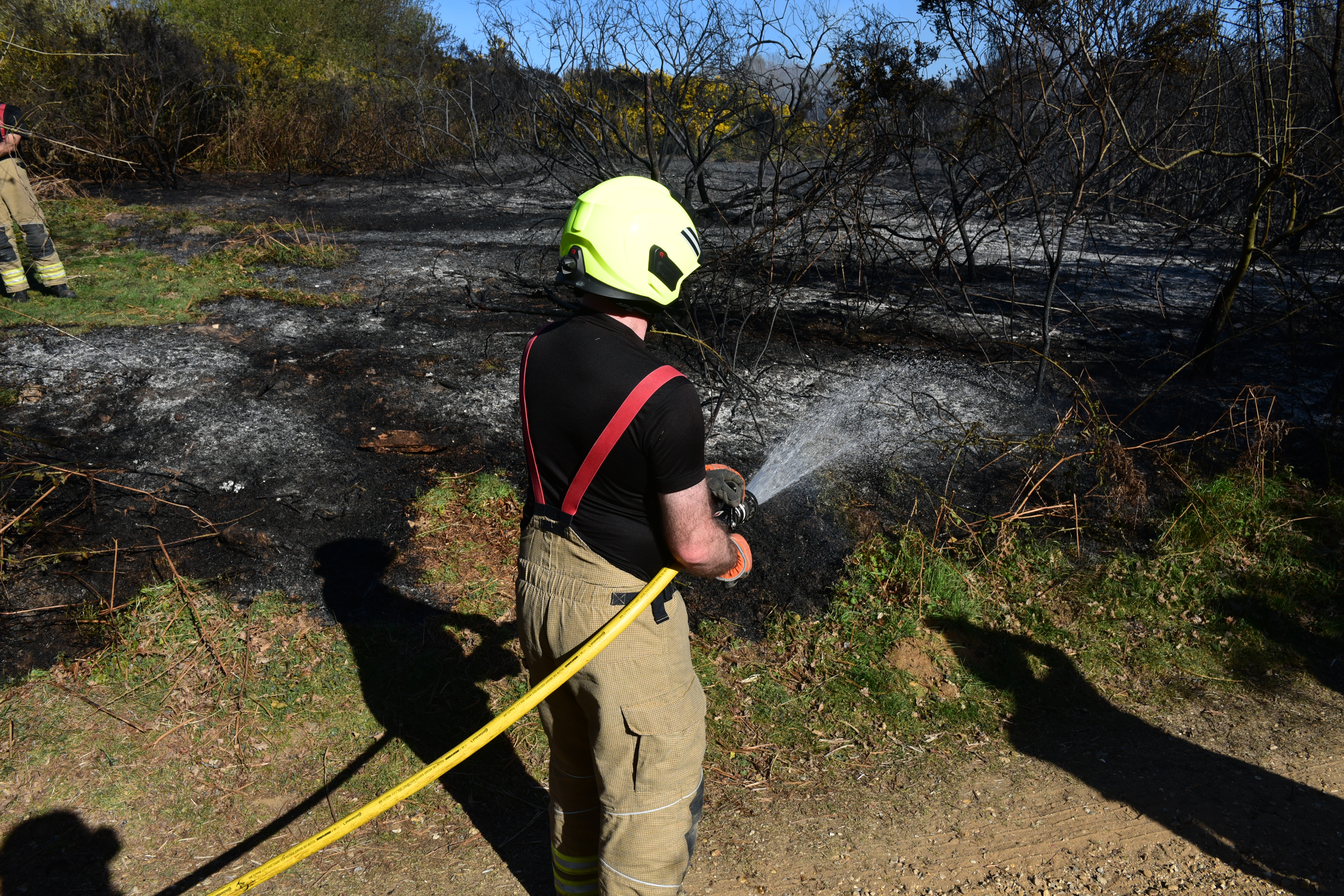 Firefighter at a gorse fire with a hose