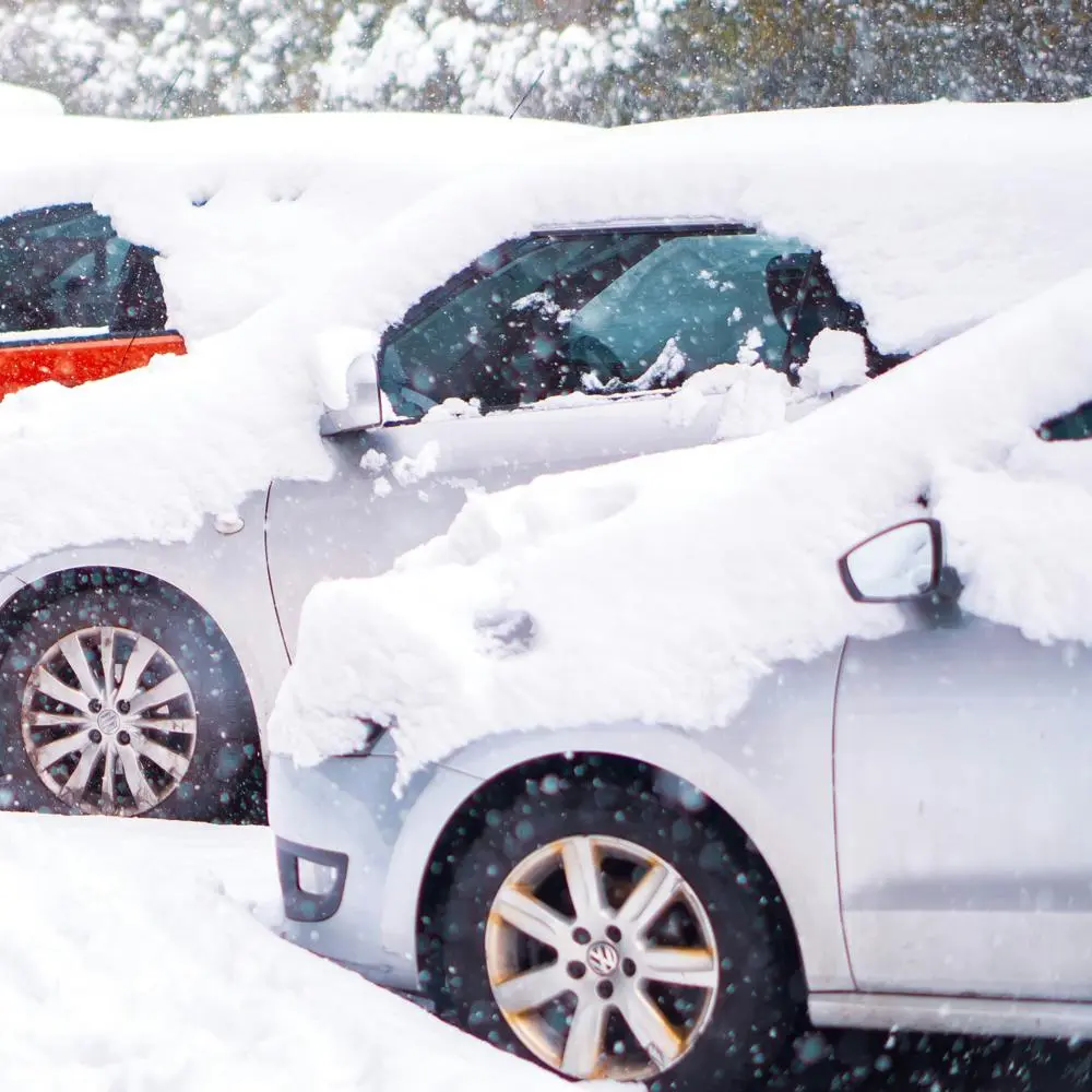 Two or three cars parked in a row, covered in heavy snow.