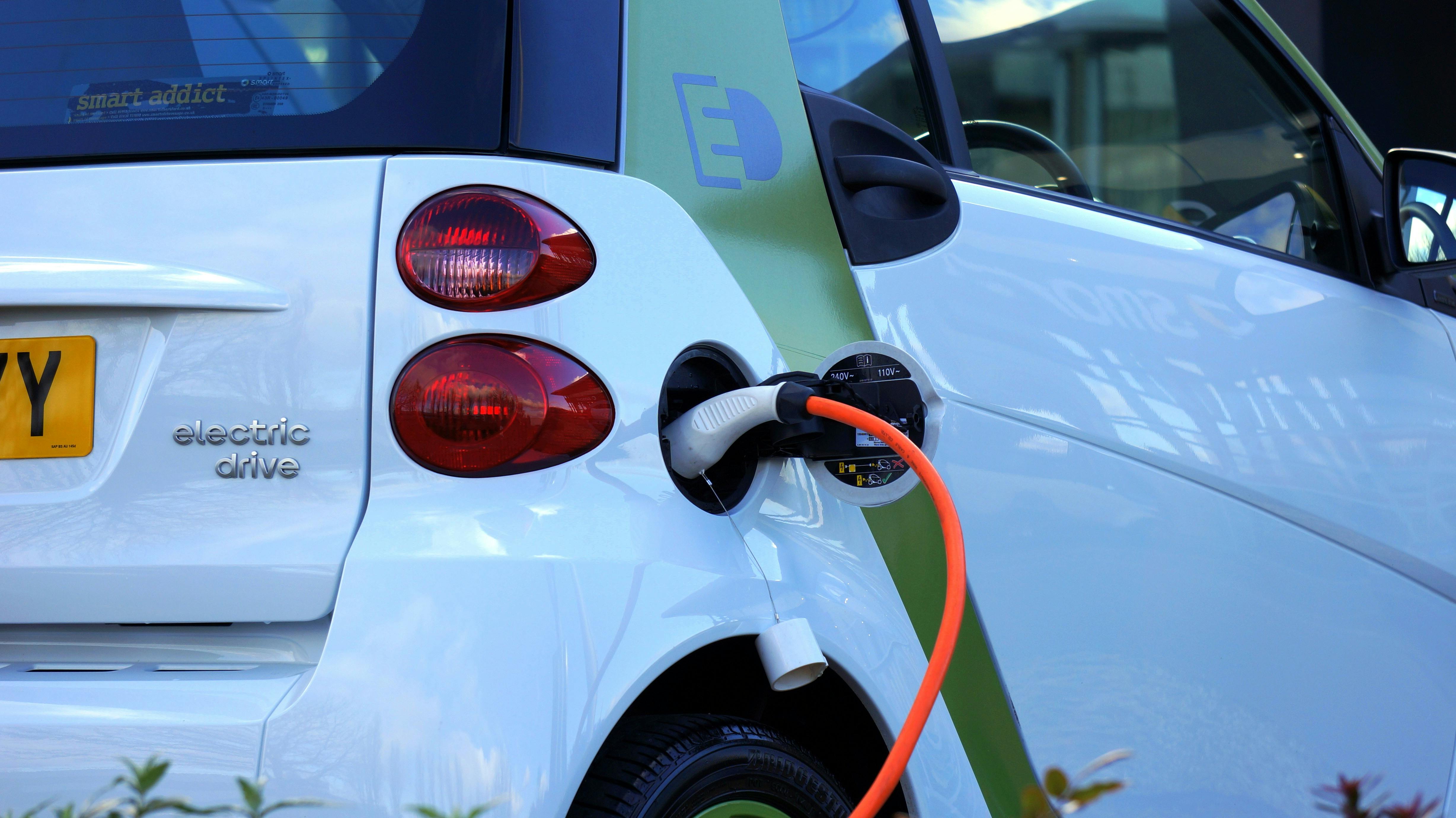 A white car charging with an orange cable. 