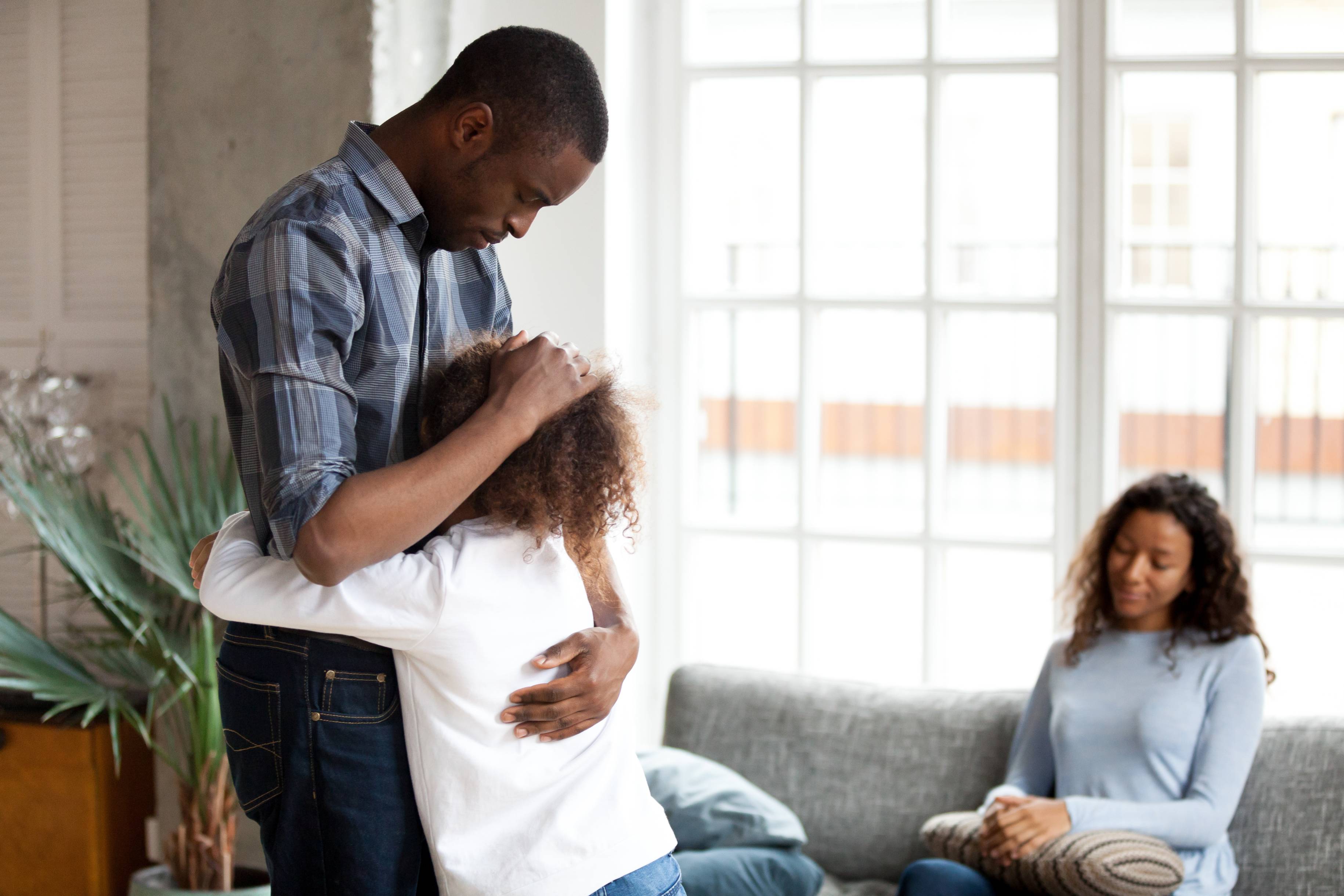 Family, mother and father, comforting their child with a hug