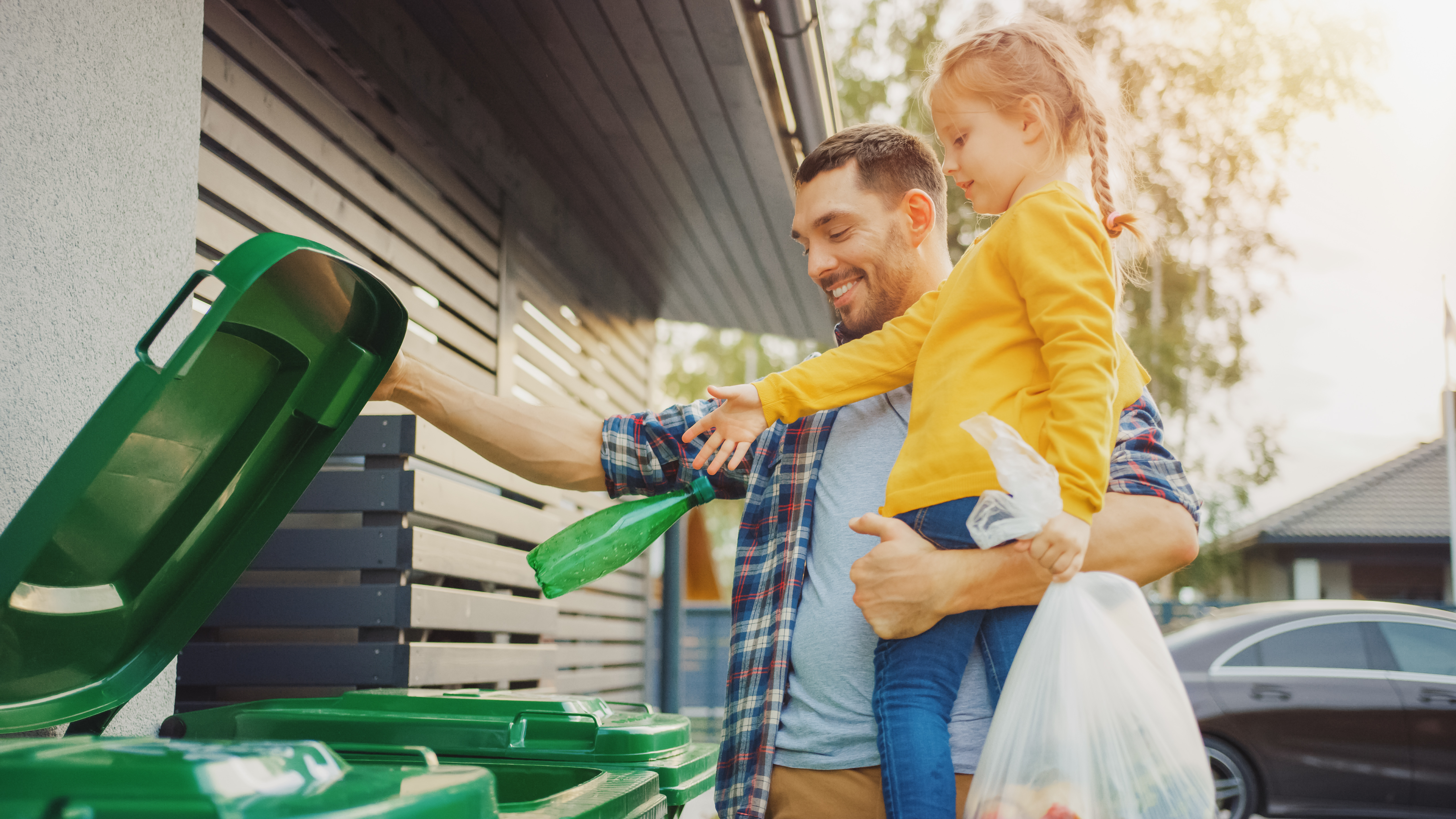 Man and daughter using the green recycle bin