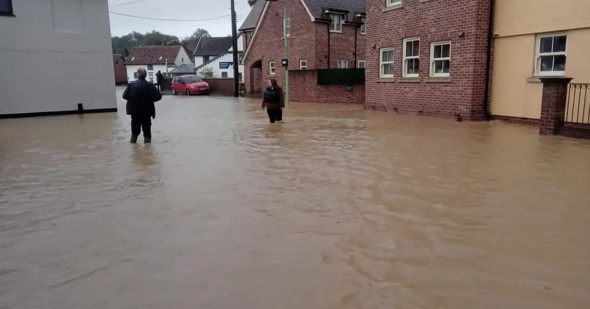 Two people knee-deep in flood water.