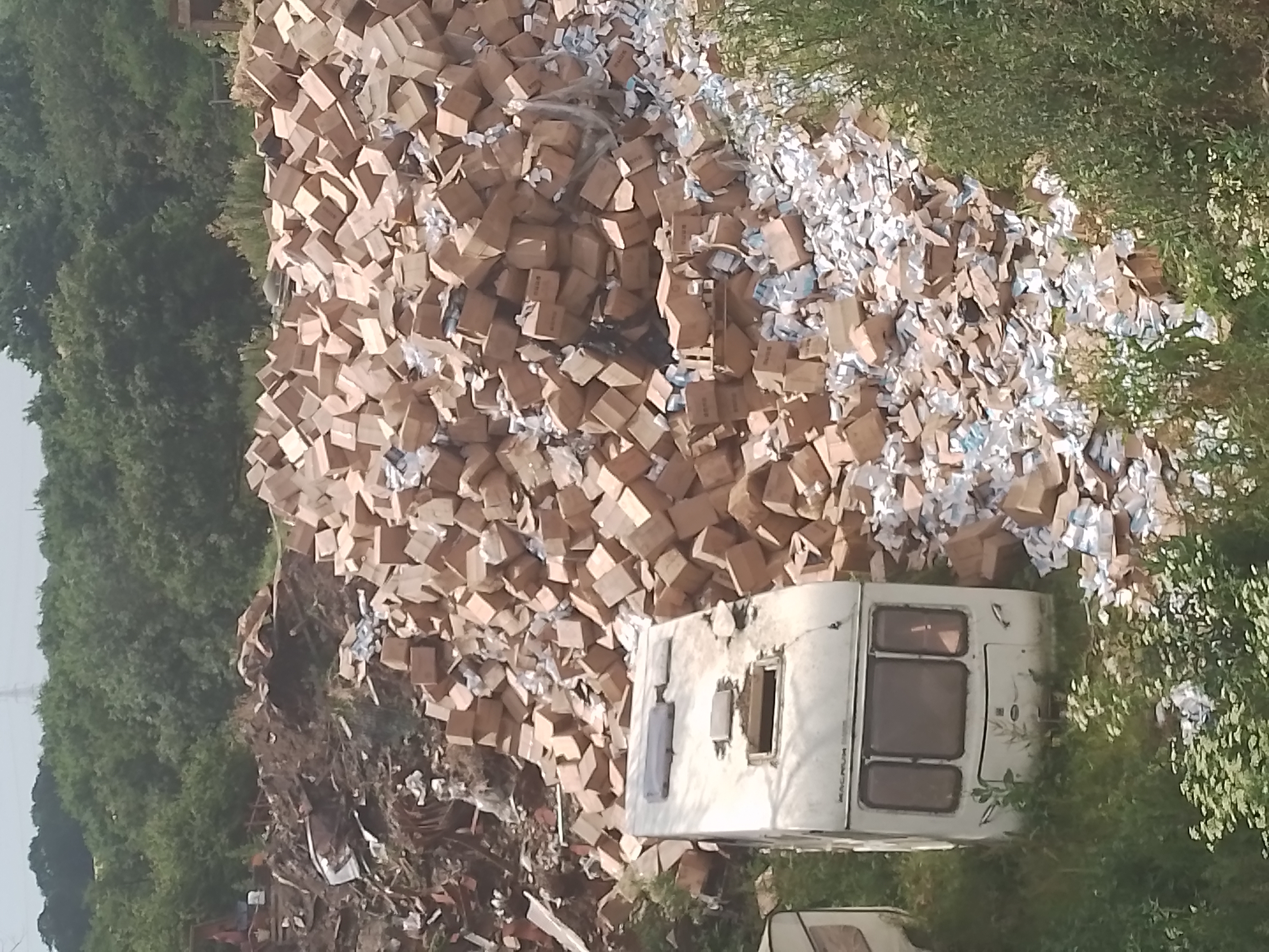 a huge pile of waste on green land, including two caravans and hundreds of full cardboard boxes