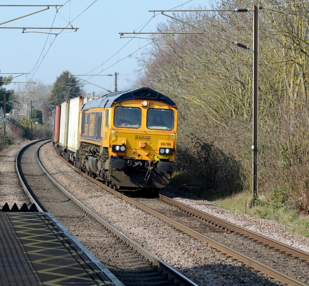 A freight train drives along the tracks pulling shipping containers
