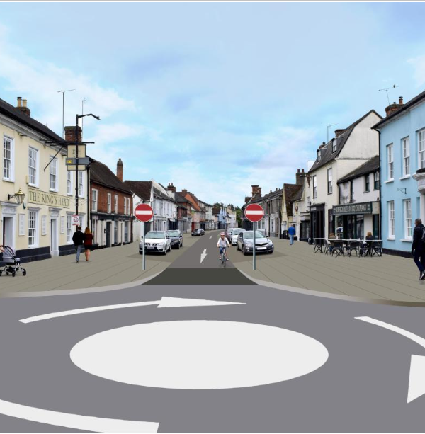 A mini roundabout with no entry signs, a cyclist and parked vehicles.
