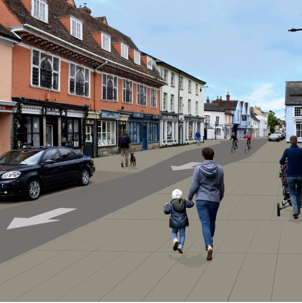 Pedestrians in a street with a car by shops.