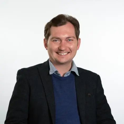 Councillor Harry Richardson wearing a black jacket, blue jumper and shirt and smiling.