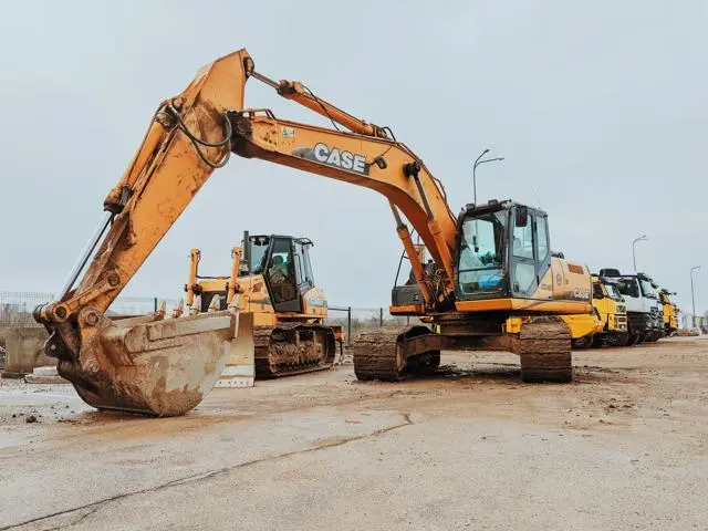 Two diggers parked in front of a row of lorries