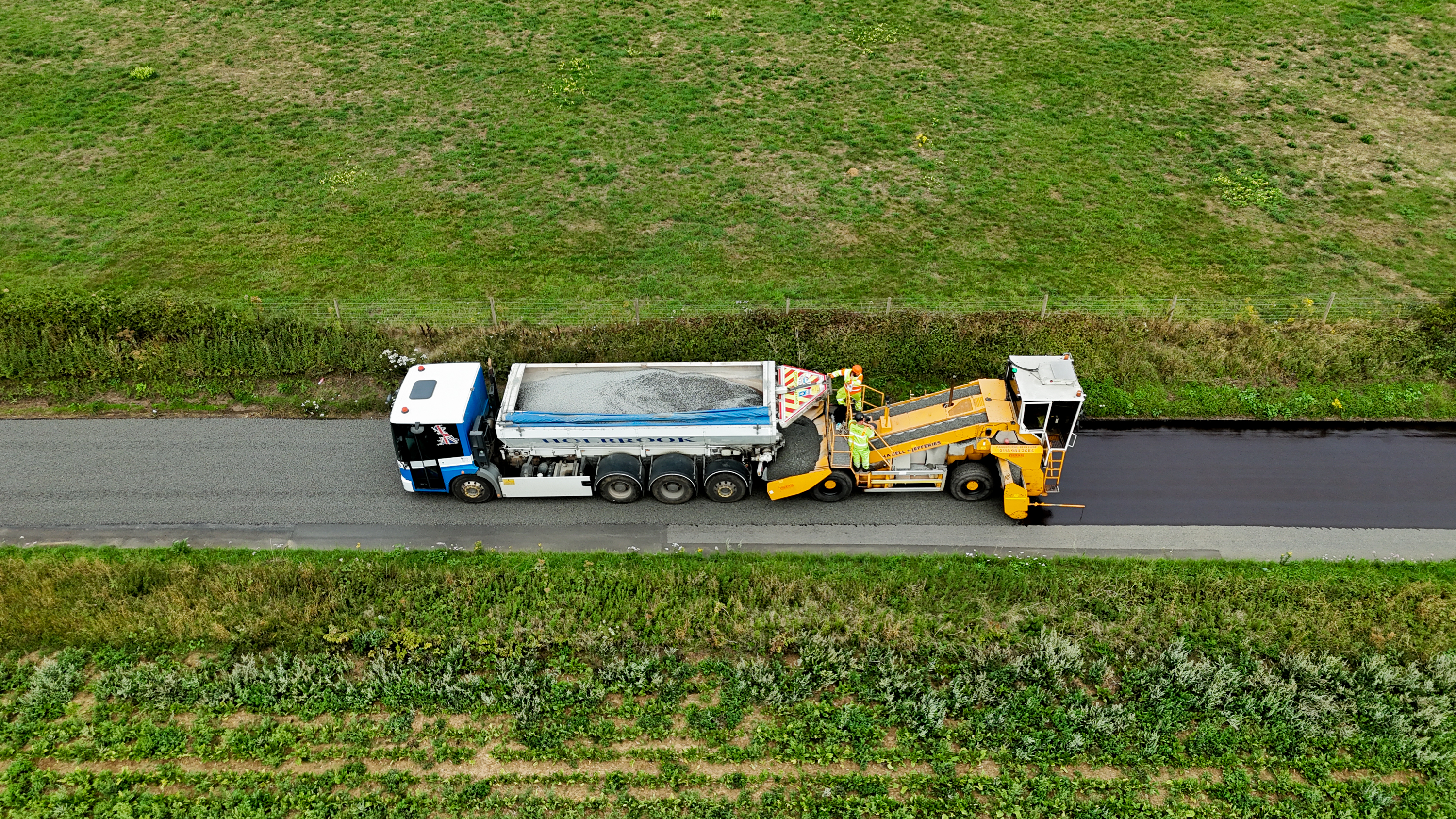 An image of highways vehicles applying surface dressing to a road