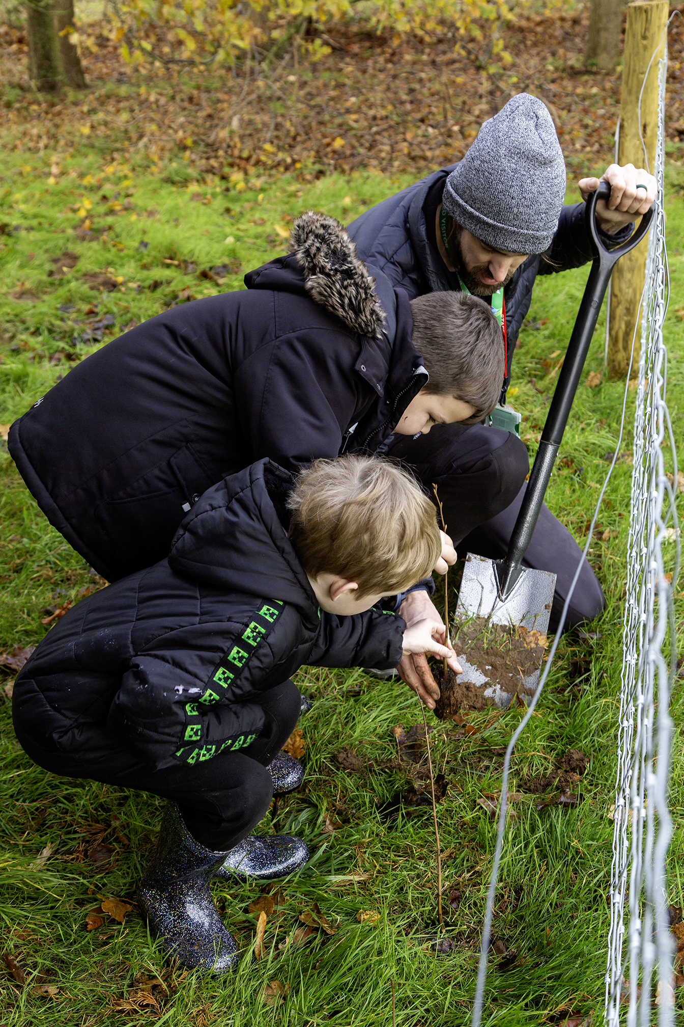 two children and an adult plant trees