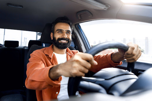 A man smiling whilst driving a car.