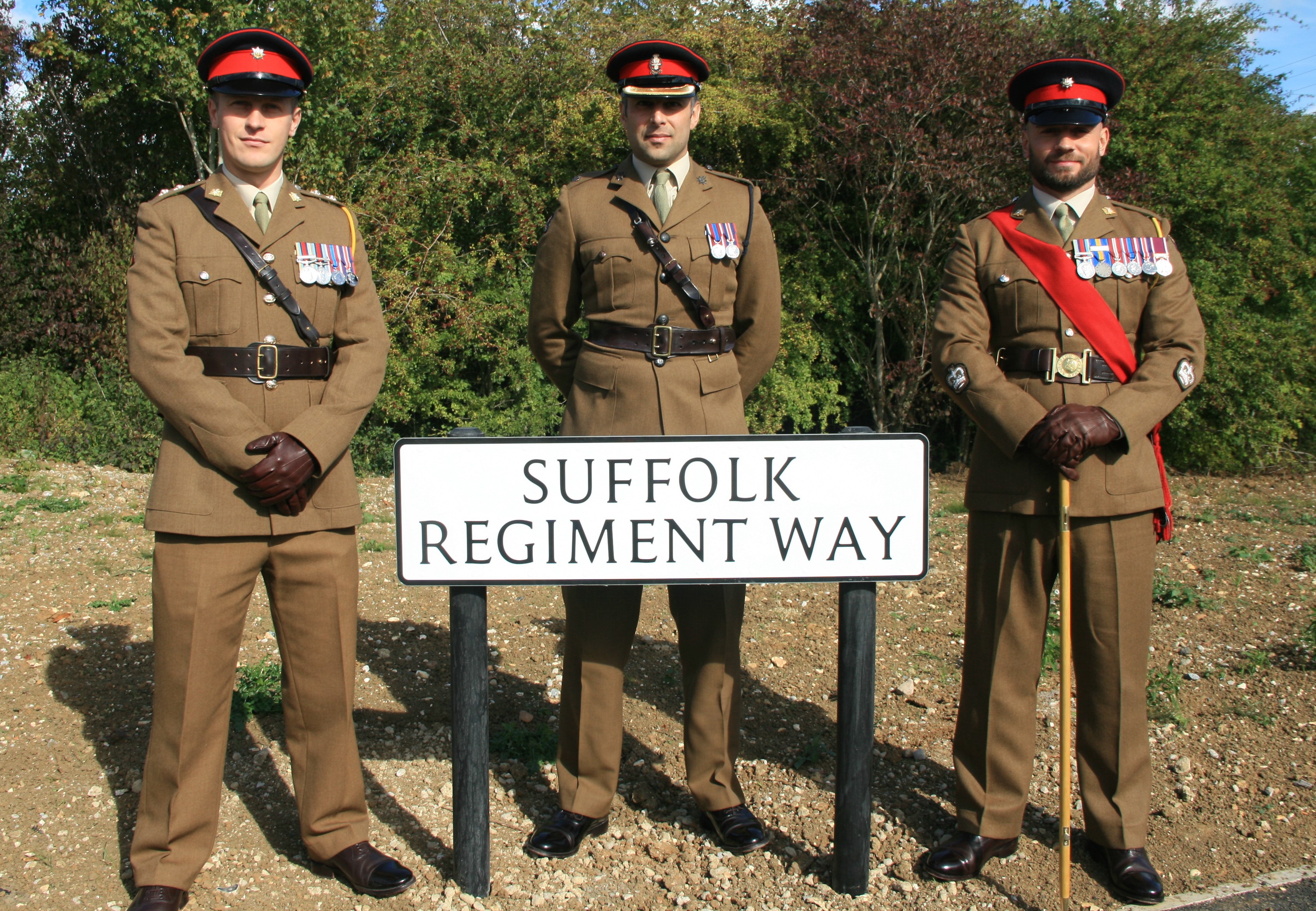 Three soldiers in dress uniform with the new Suffolk Regiment Way road sign