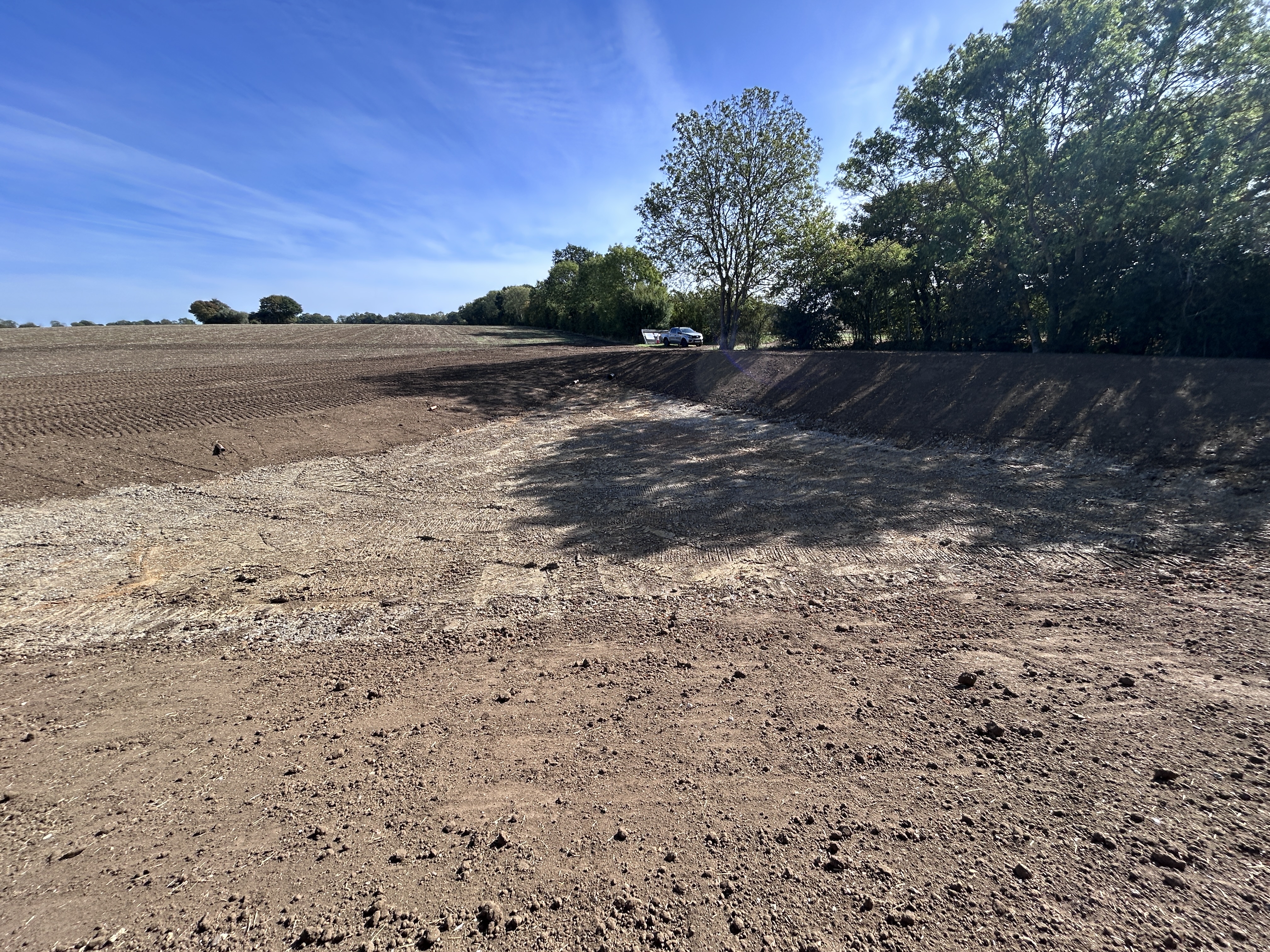 a large dug out area in a field near trees