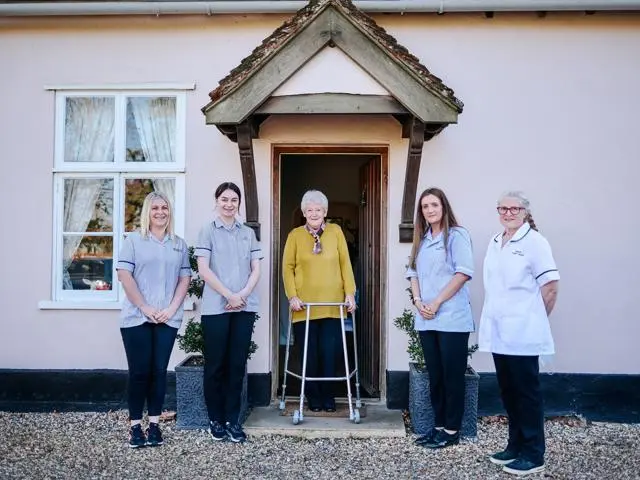 Four care workers standing outside a house with a woman