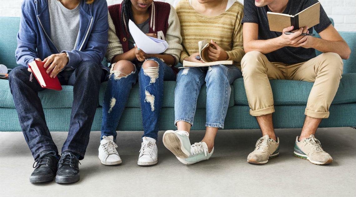 4 teenagers sitting on a sofa with books