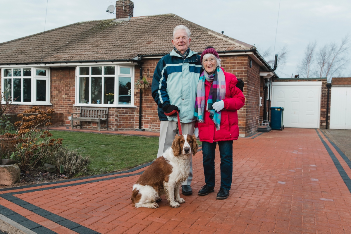 independent older couple outside their home with their dog 