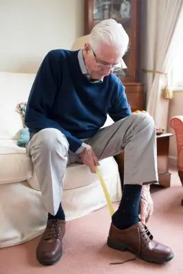 Older man using shoehorn