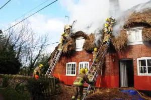 Image of firefighters extinguishing a thatched roof on fire