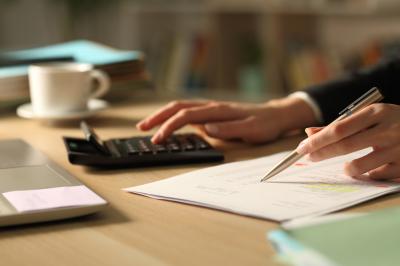 woman using calculator and writing notes on paper