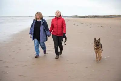 Female couple walking on the beach with a dog