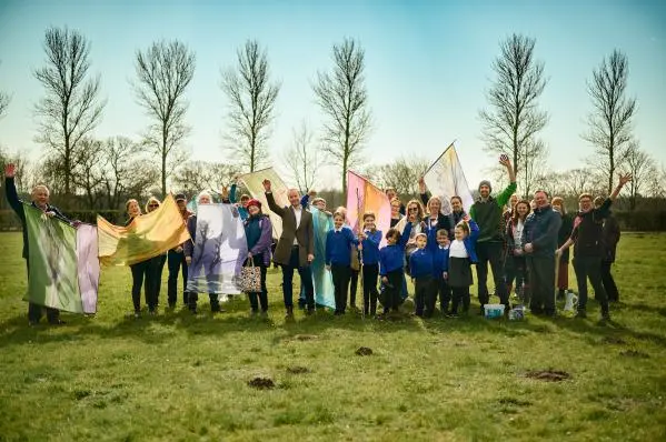 Teachers and Students at Howard Academy wave in front of newly planet trees.